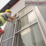 Contractor installing exterior replacement windows on a ladder